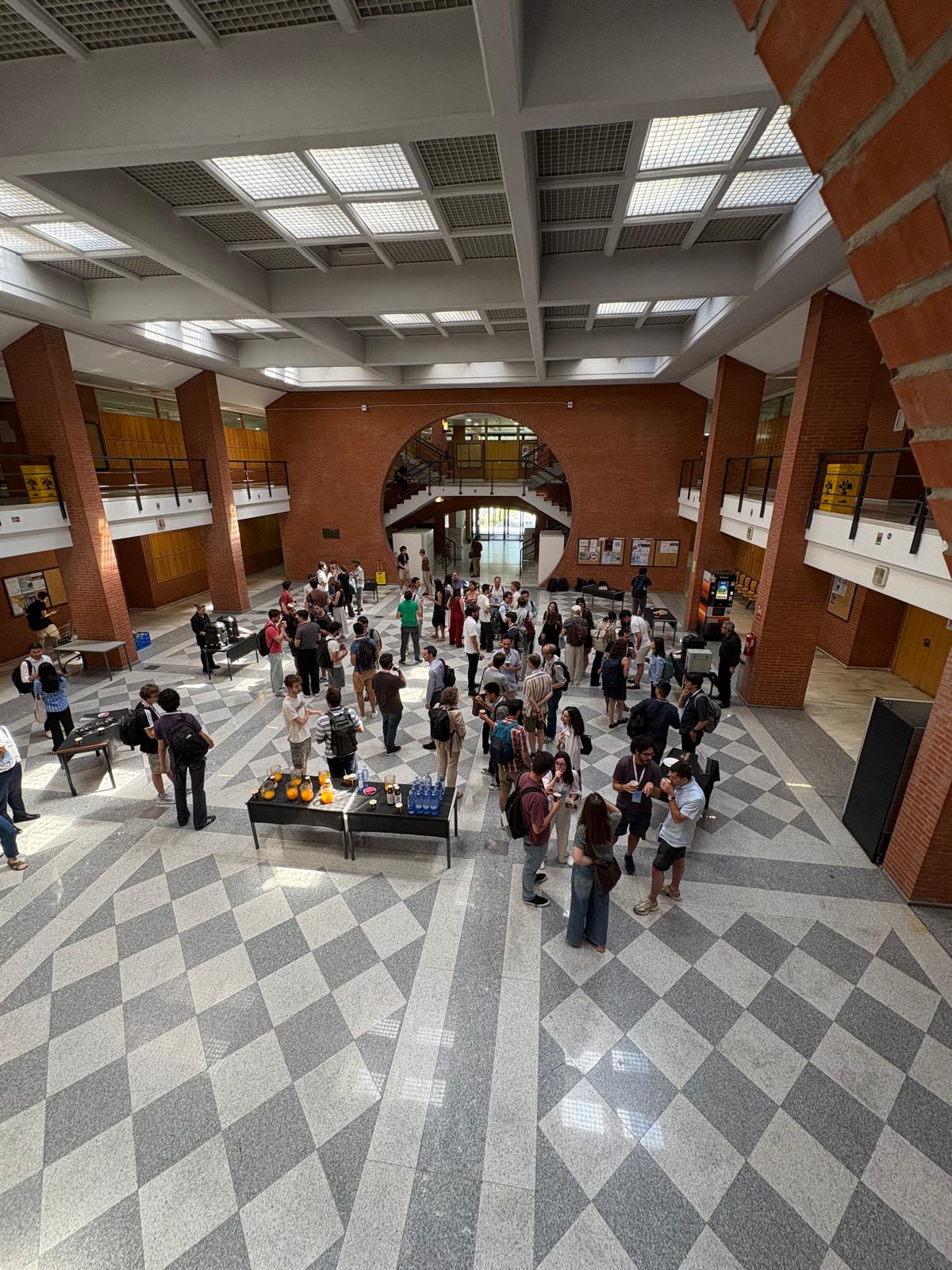 Asistentes durante la pausa del café en el hall del edificio 14